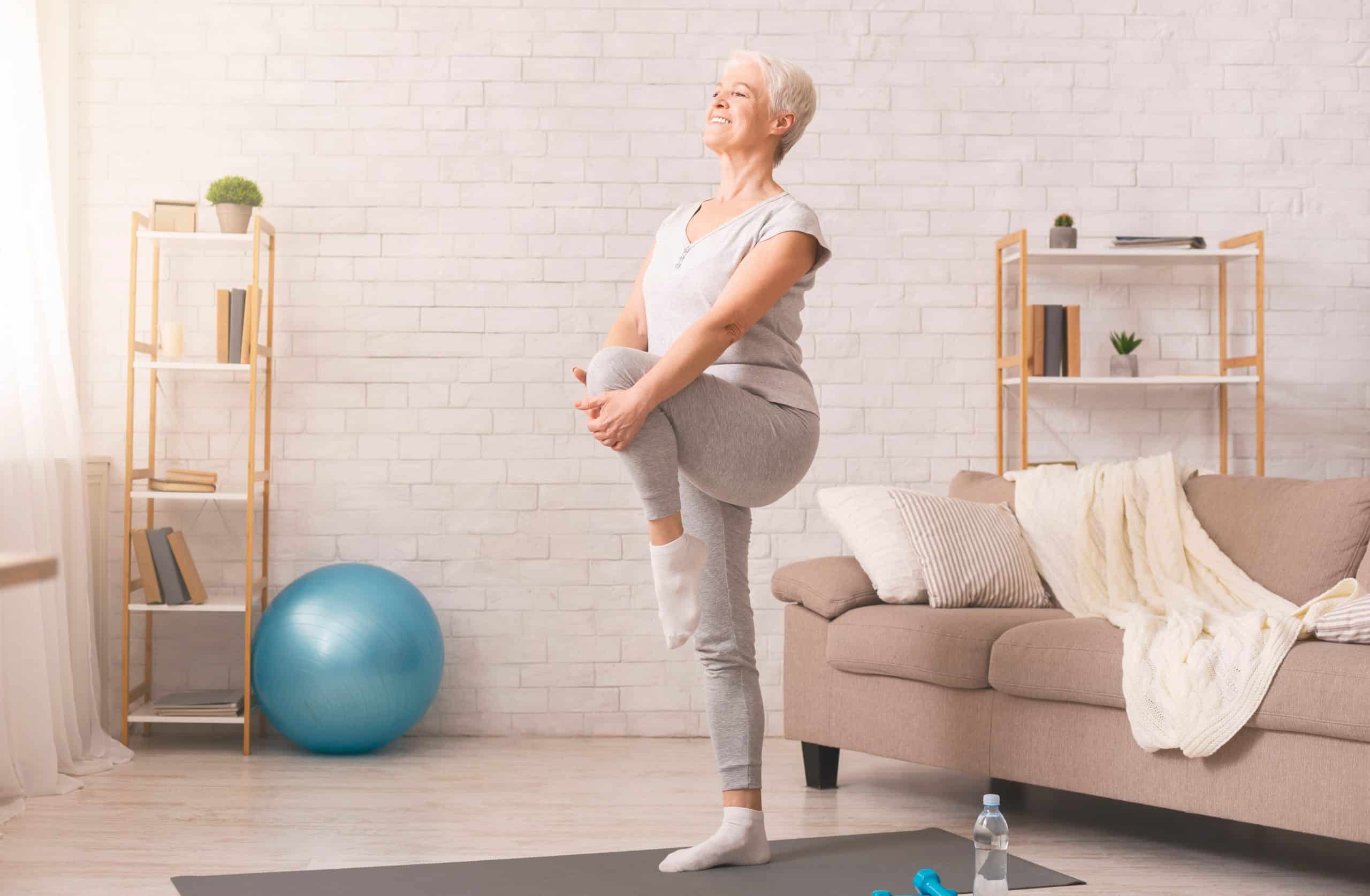 Active senior woman doing legs exercise at home