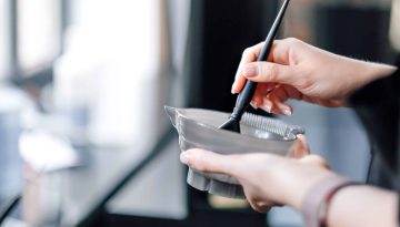 Hairdresser holding bowl with hair dye in beauty salon