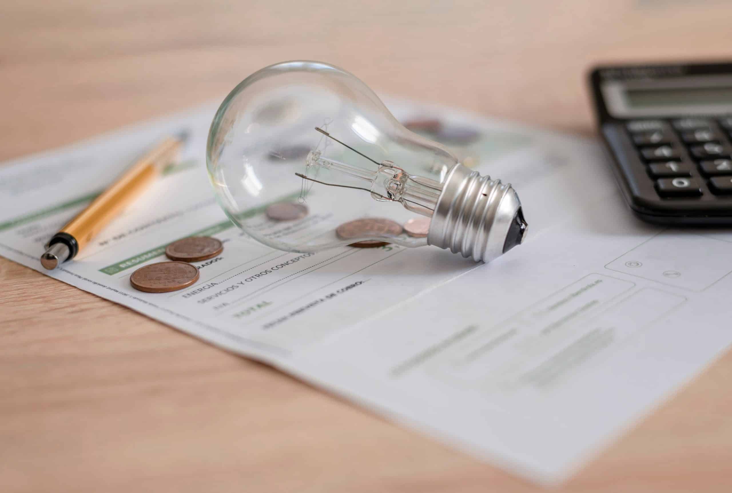 Electricity bill with light bulb, several coins, calculator and