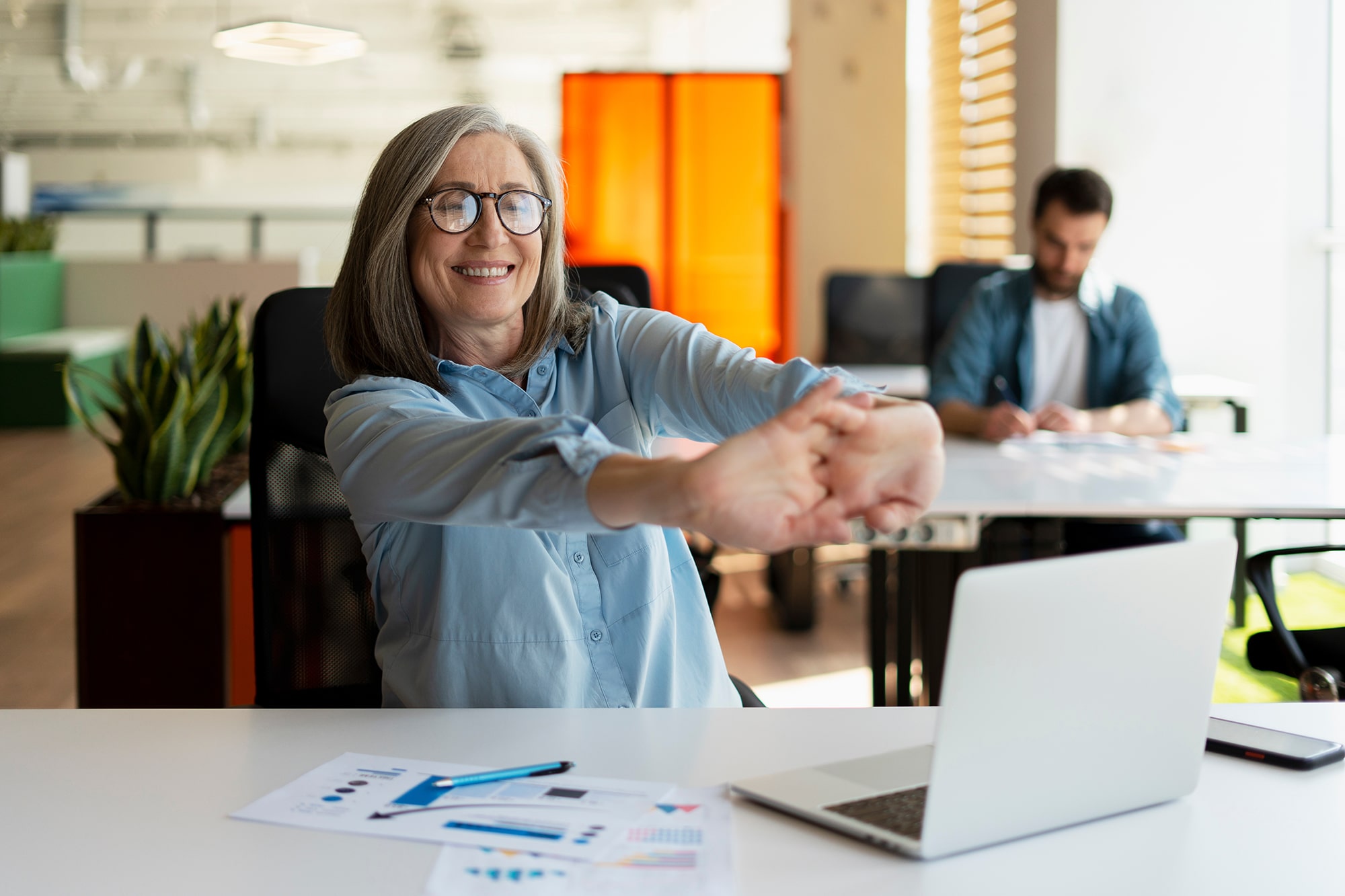 Portrait of smiling senior woman using laptop stretching arms, r