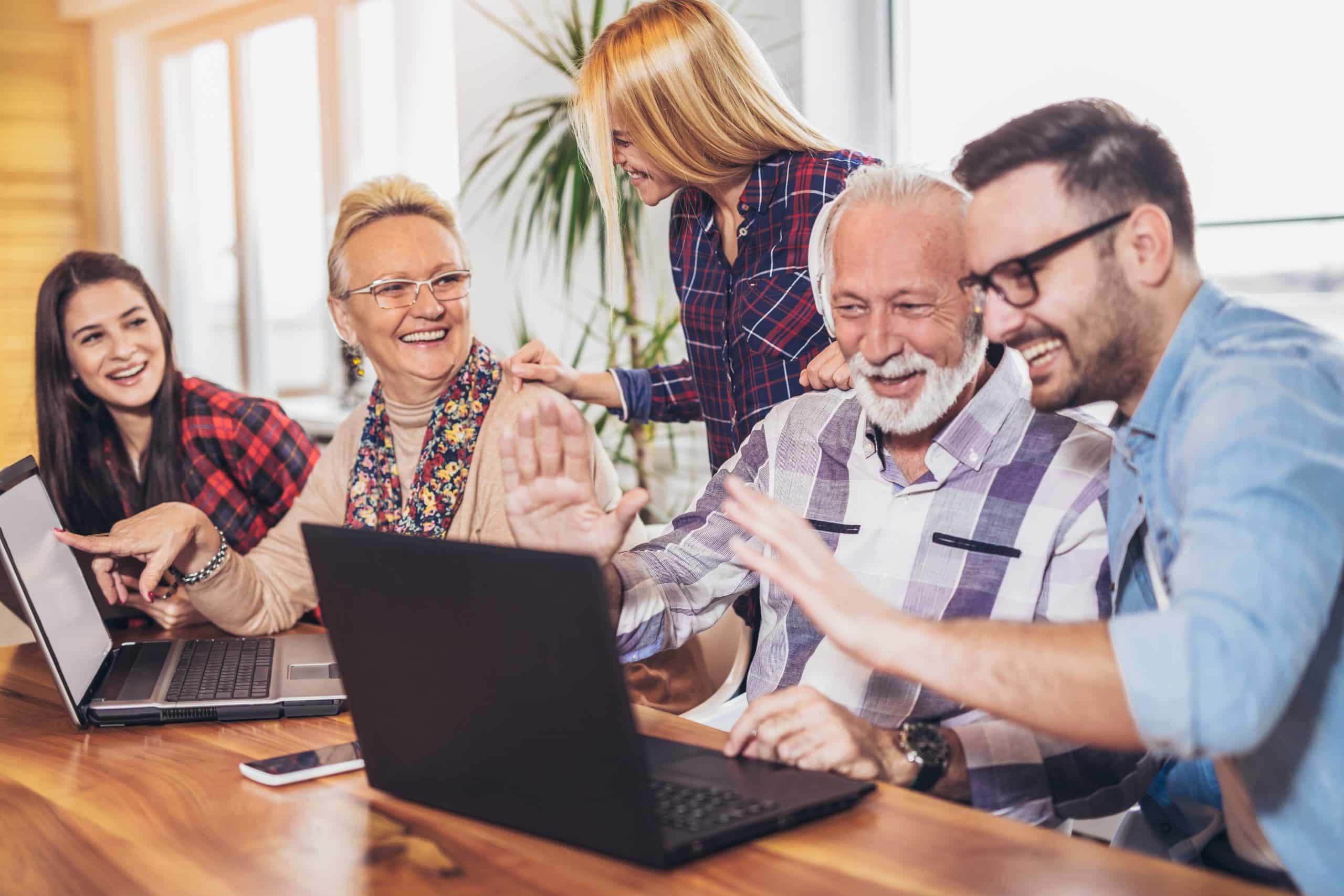 Young volunteers help senior people on the computer. Young peopl