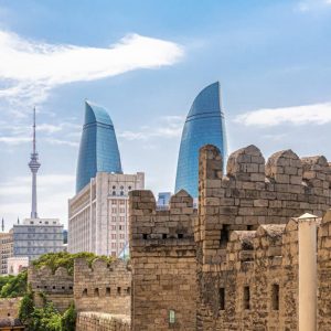 Baku, Azerbaijan, 07.26.2019. Fortress walls of the old city, view of the Flame towers and TV tower, against the blue sky